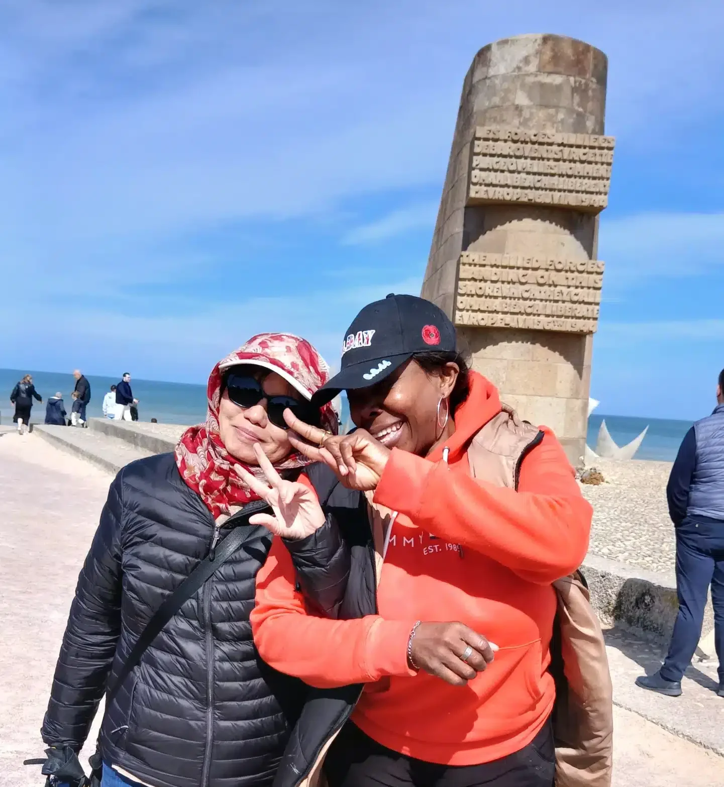 Deux clientes souriantes profitant d'une excursion touristique à Omaha Beach, service de transport VTC Borel Royal.